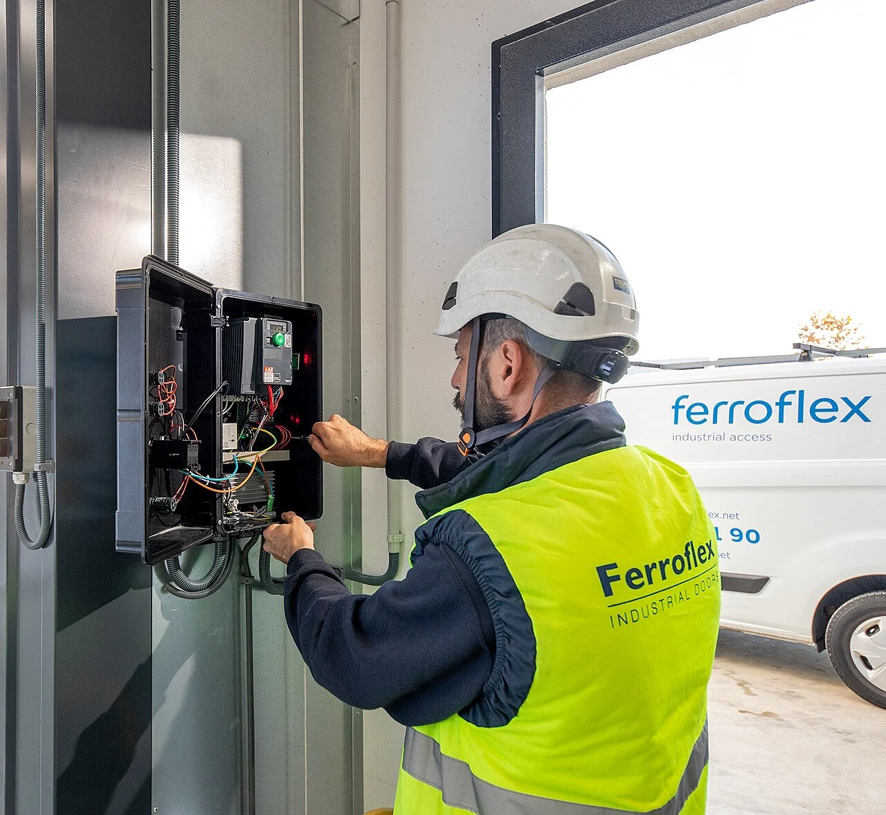 An electrician working inside an open electrical control panel