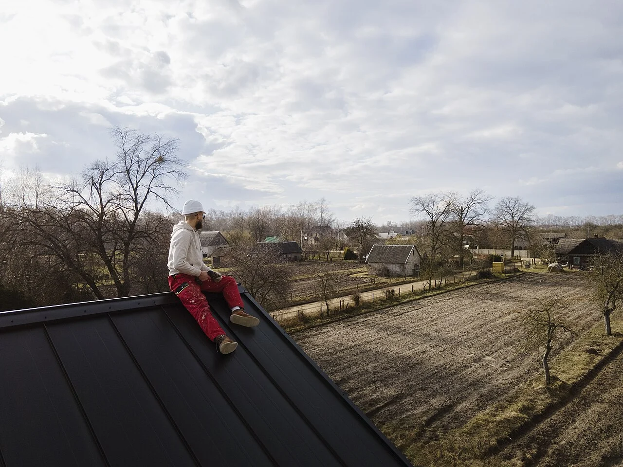 A worker on a standing-seam metal roof at a rural property