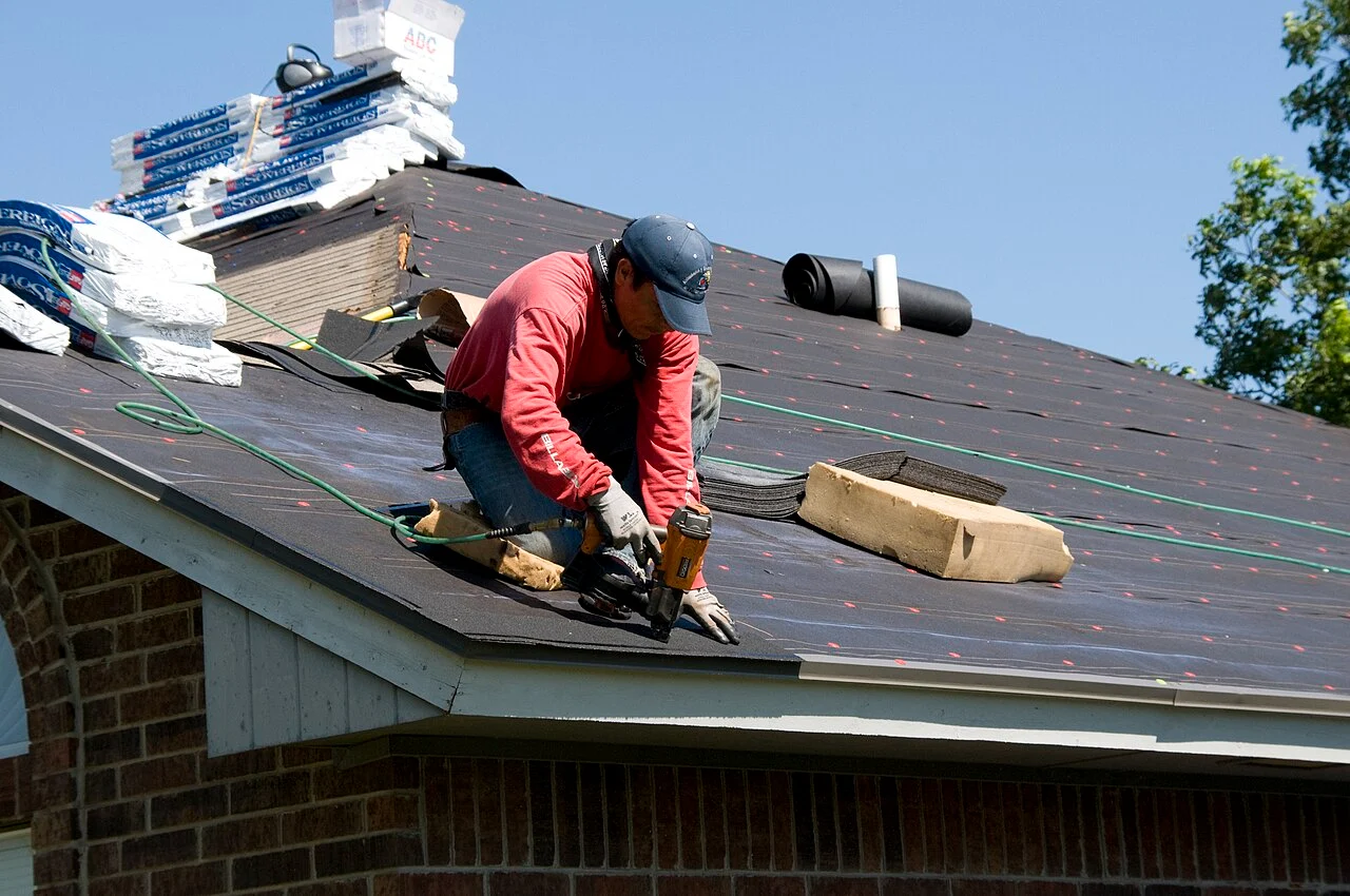 A roofer fastening underlayment on a residential roof in Oklahoma